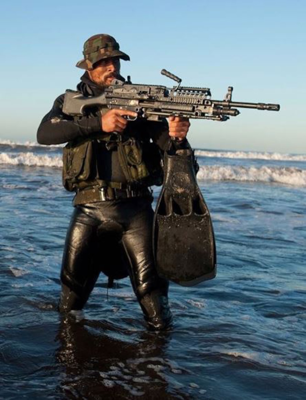 A man stands in the water with a big gun.