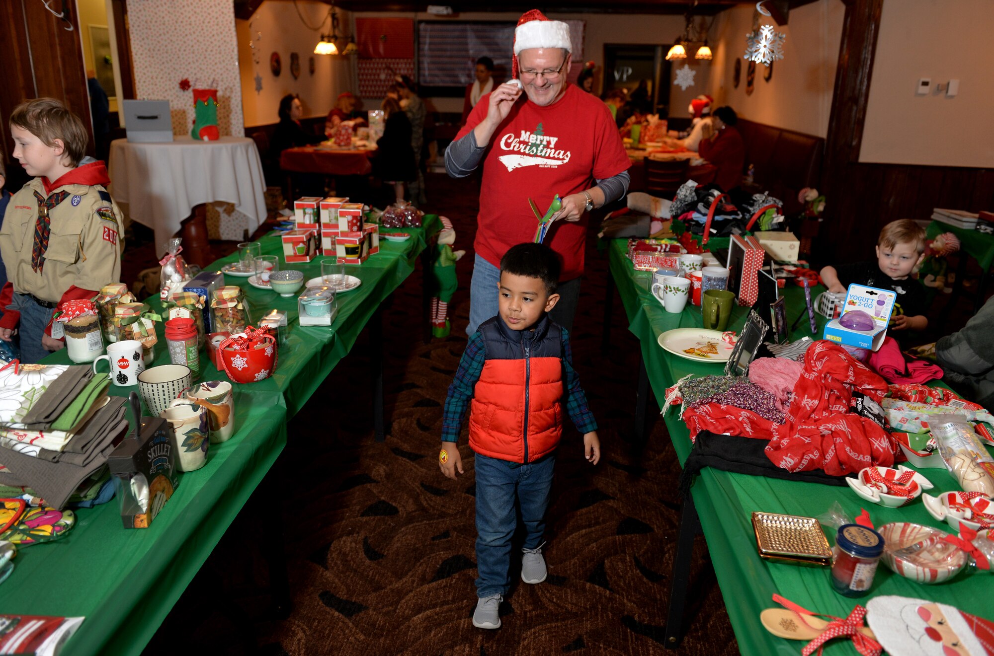Five-year-old Kai, son of Airmen 1st Class Erik, 20th Intelligence Squadron, peruses the ‘Elf Mart’ during the annual Offutt Christmas Tree Lighting event held at the Patriot Club, Offutt Air Force Base, Nebraska, Dec. 6, 2018. For a small fee, children were able to shop and wrap gifts for their parents who were waiting in the next room. (U.S. Air Force photo by Josh Plueger)