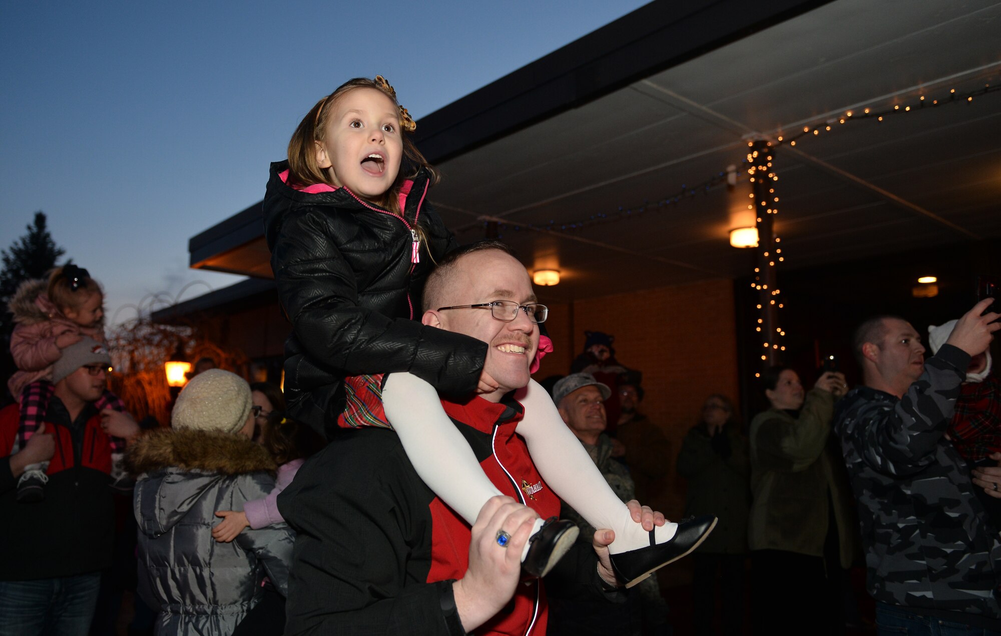 Four-year-old Bella, daughter of Master Sgt. Jacob Downing, 55th Force Support Squadron Offutt Field House section chief, sits atop her dad’s shoulder’s to see Santa Claus arrive at the Offutt Christmas Tree Lighting event at the Patriot Club, Offutt Air Force Base, Nebraska, Dec. 6, 2018.  The annual event garners a large turnout of members of the Offutt community. (U.S. Air Force photo by Josh Plueger)