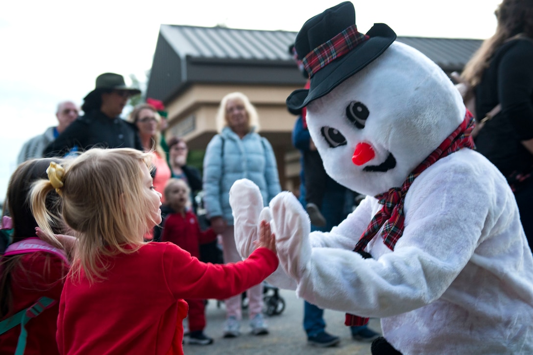 An attendee high-fives a mascot during the Tree Lighting Ceremony, Nov. 30, 2018, at Moody Air Force Base, Ga. The event continues the tradition of families of deployed Airmen lighting the base Christmas tree. As a way to celebrate the sacrifices of Team Moody Airmen and their families, the base also hosted a parade and other holiday festivities. (U.S. Air Force photo by Airman 1st Class Erick Requadt)