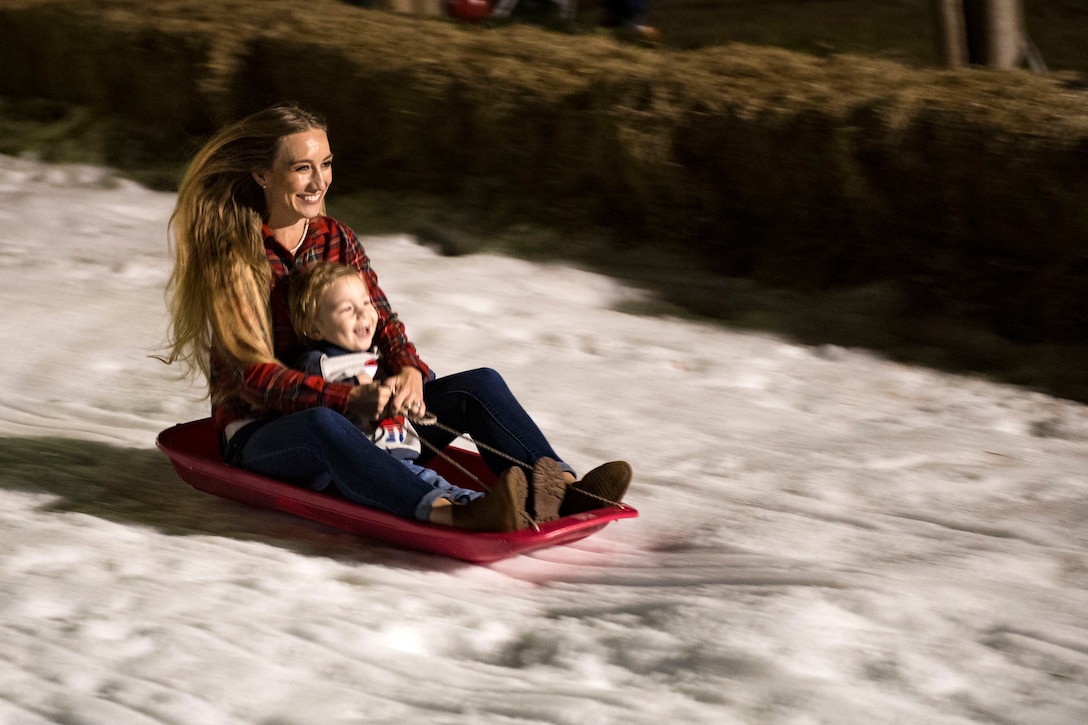 Attendees sleigh down a hill during the Tree Lighting Ceremony, Nov. 30, 2018, at Moody Air Force Base, Ga. The event continues the tradition of families of deployed Airmen lighting the base Christmas tree. As a way to celebrate the sacrifices of Team Moody Airmen and their families, the base also hosted a parade and other holiday festivities. (U.S. Air Force photo by Airman 1st Class Erick Requadt)