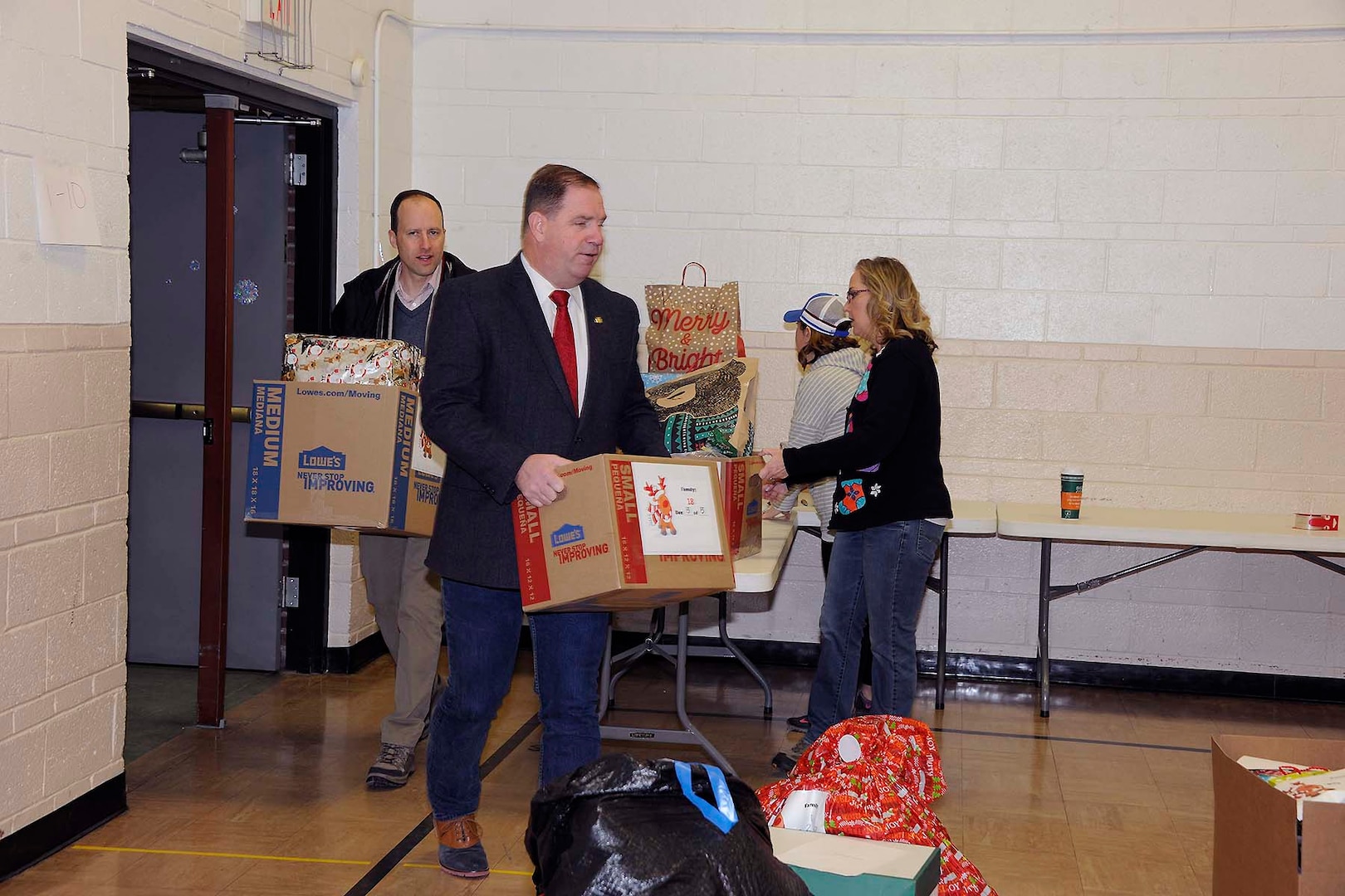 DLA Disposition Services Director Mike Cannon (center) carries a box of donations into the staging area as other volunteers take in more items.