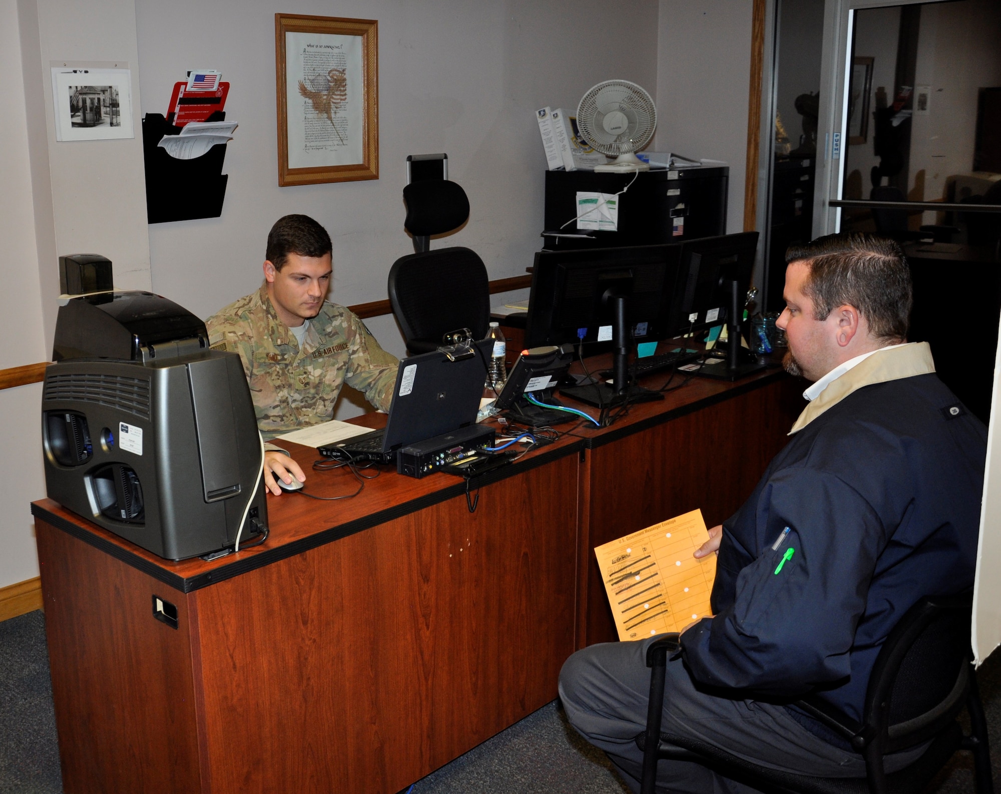 Staff Sgt. Eric Duke logs in information from customer Sargent Engle IV for a restricted area/controlled area badge at the 88th Security Forces Pass and Registration office in Area A, Building 286.