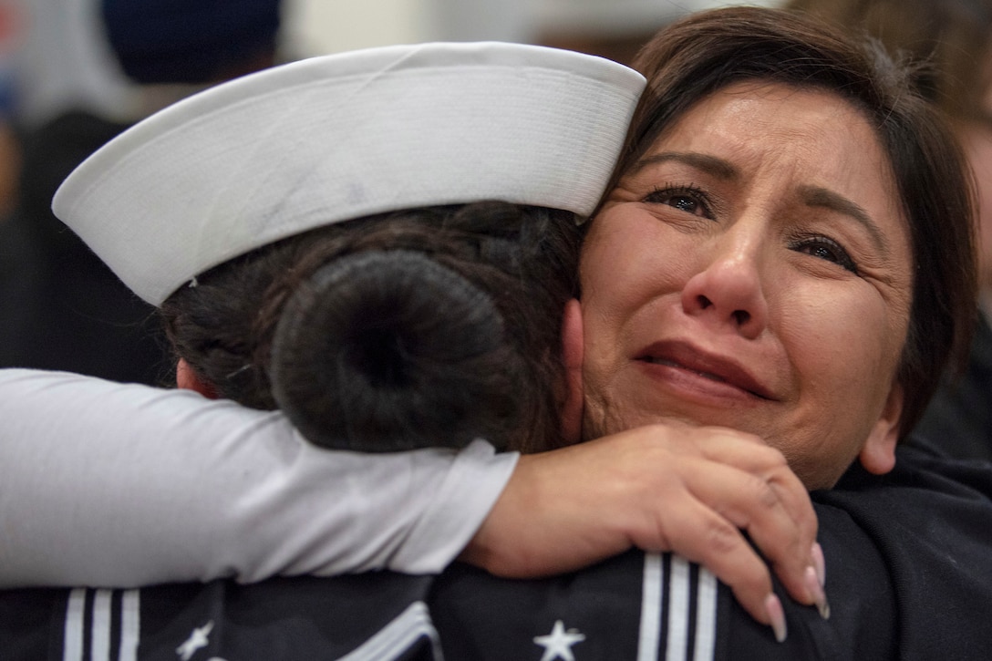 A sailor is hugged by a woman.
