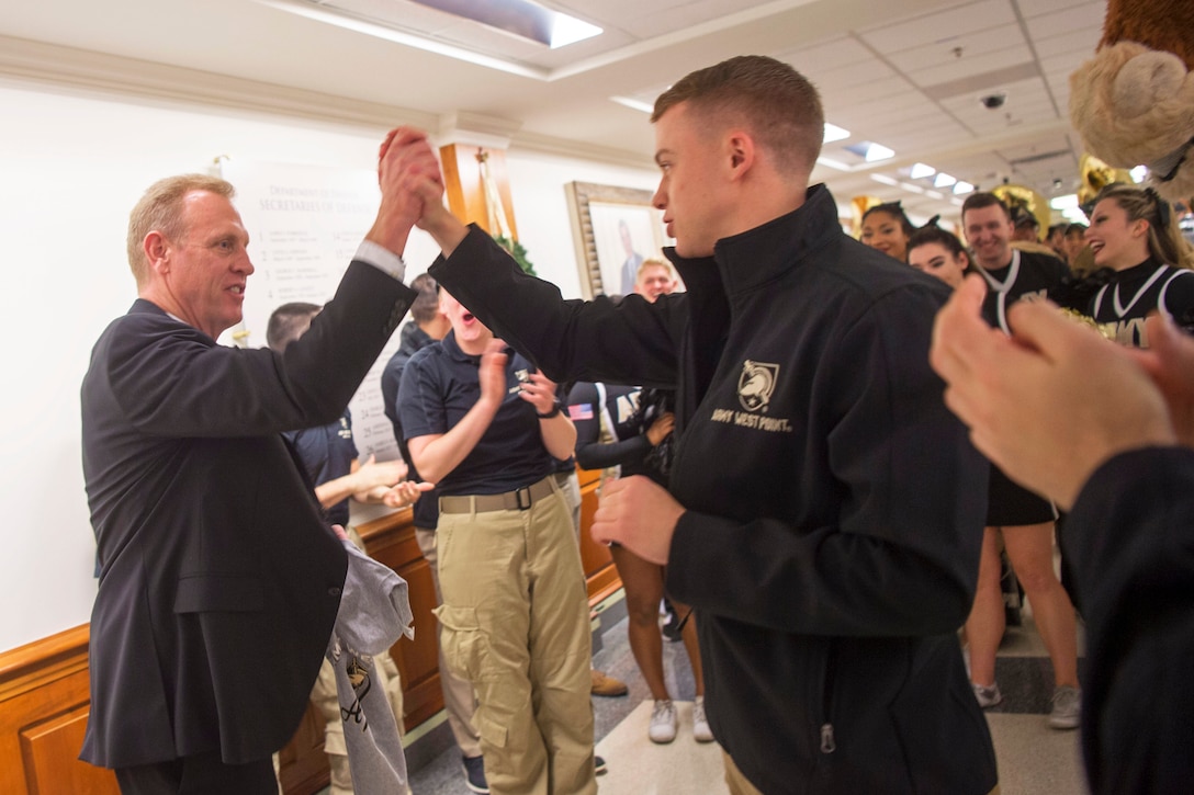 Deputy Defense Secretary Patrick M. Shanahan high-fives an athlete during a pep rally.