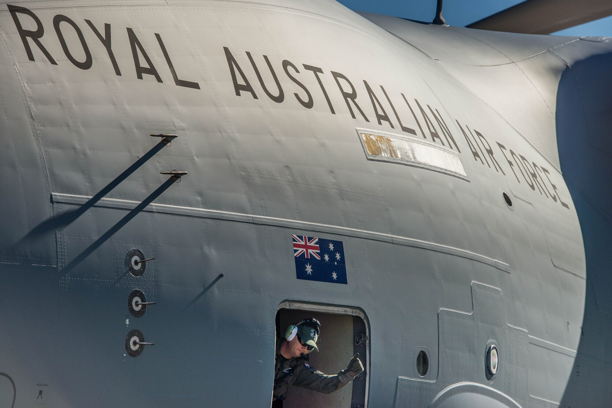 A Royal Australian Air Force airman waves goodbye before closing the door on a C-17 Globemaster III at Luke Air Force Base, Ariz., Dec. 3, 2018. The RAAF loaded the aircraft with airmen and supplies in preparation for their multi-day journey to Australia. The Globemaster is scheduled to follow two F-35A Lightning II’s for their historic arrival in Australia. (U.S. Air Force photo by Staff Sgt. Jensen Stidham)