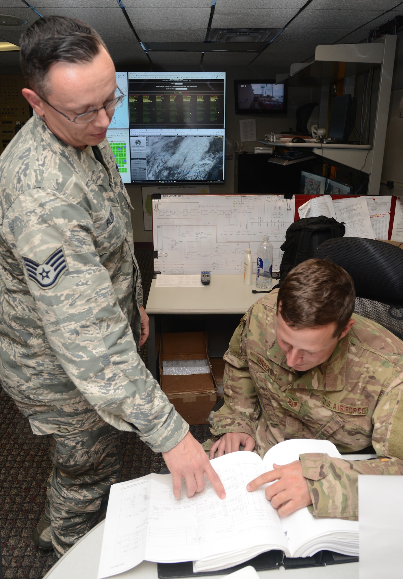 Staff Sgt. Curt Filkins II and Tech. Sgt. Chris Marek, with the Radar Operations Center in Norman, look up technical data of a radar system.