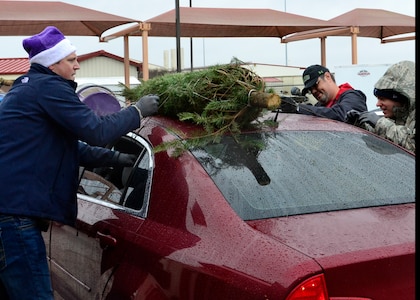 Maj. Lane Garman, 99th Flying Training Squadron, Director of Staff assists fellow volunteers, Mr. Robert Butler, Air Force Personnel Center, Human Resources and Capt. Jeromy McElwaney, 99th Flying Training, Squadron Executive, tie a tree down to a car during the Trees for Troops event at Joint Base San Antonio-Randolph, Texas, Dec. 7, 2018.