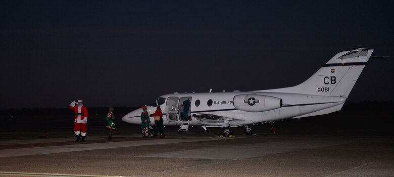 Santa Claus and three of his elves exit a T-1A Jayhawk, Dec. 4, 2018, on Columbus Air Force Base, Mississippi. Santa then hopped on a fire truck and led a walking parade to the BLAZE Chapel where members of Team BLAZE lit the base‘s Christmas tree and the third candle on the Menorah. (U.S. Air Force photo by Airman Hannah Bean)