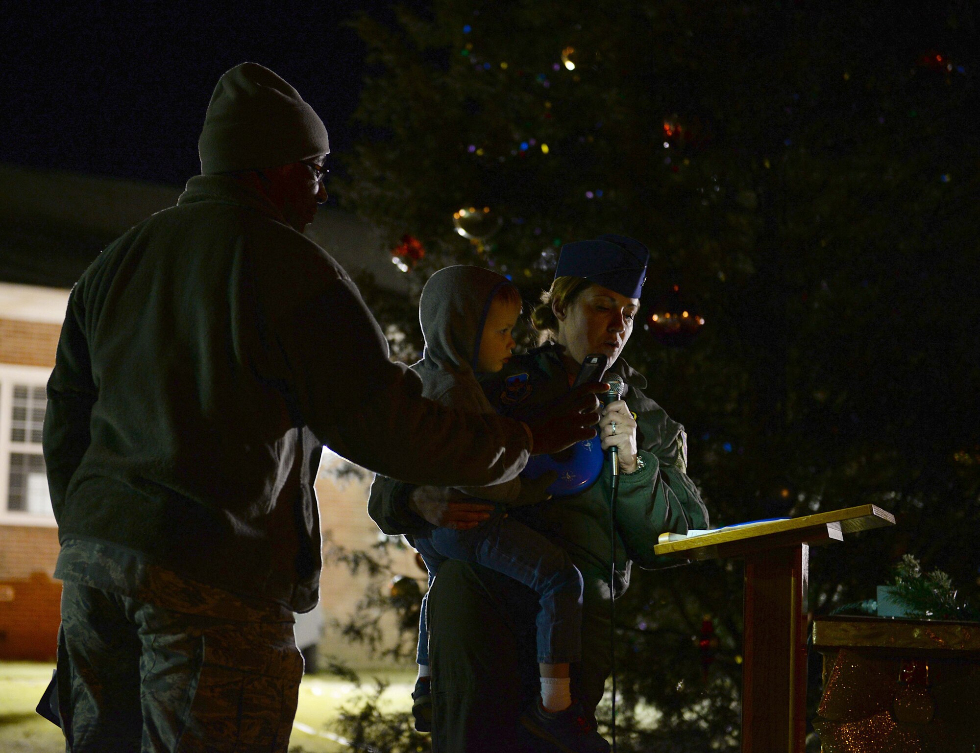 Col. Samantha Weeks, 14th Flying Training Wing Commander, accompanied by her son Ryan and Chaplain (Capt.) Timmie Henson, 14th Flying Training Wing chaplain, speaks at the Base Christmas Tree Lighting Dec. 4, 2018, on Columbus Air Force Base, Mississippi. Weeks spent the time highlighting the importance of connecting between Airmen, civilians and families. (U.S. Air Force photo by Airman Hannah Bean)