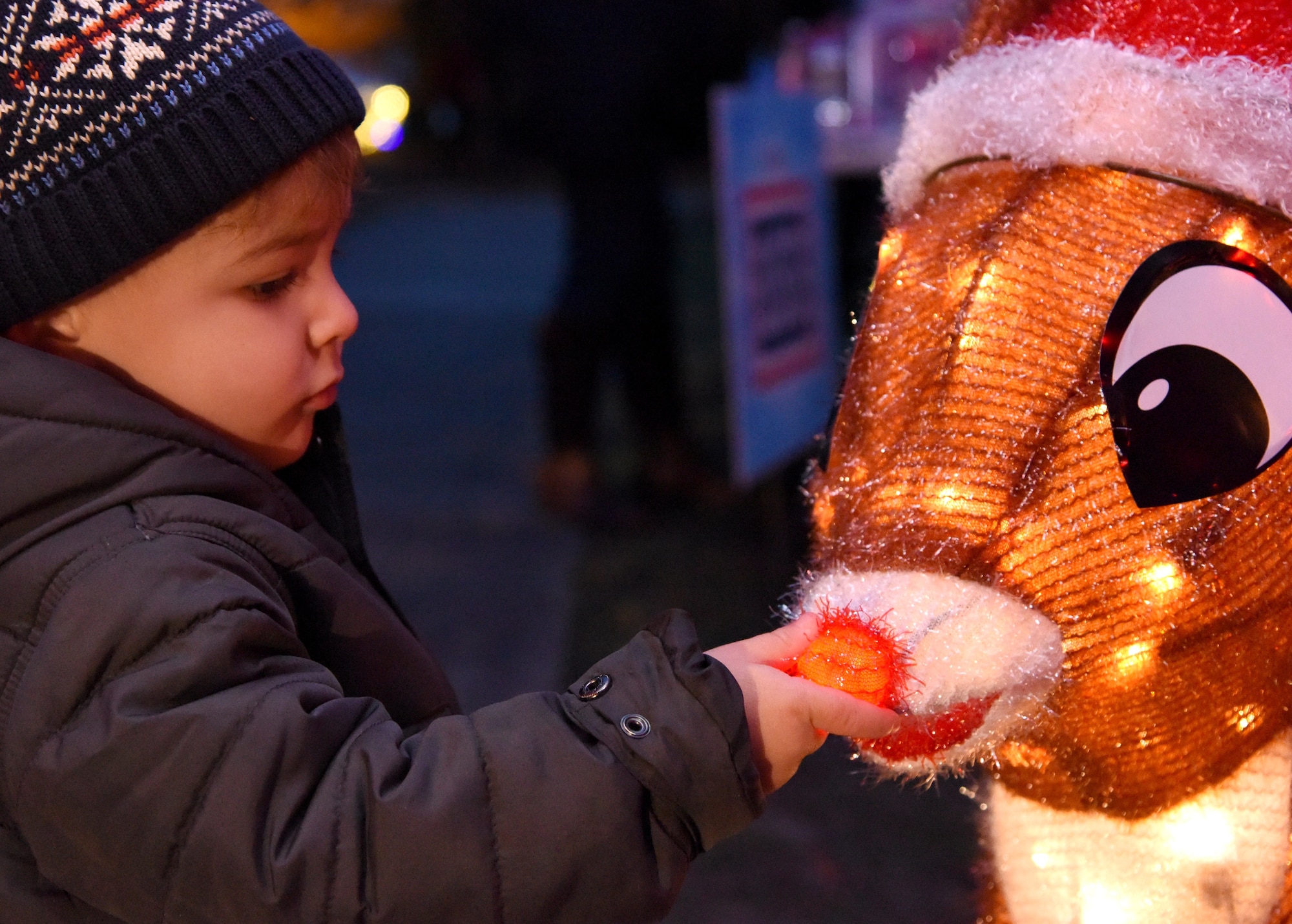 Grayson Ramirez, son of U.S. Navy Aerographers Mate 2nd Class Kadia Lazenby, Center For Naval Aviation Technical Training Unit Keesler, inspects Rudolph's nose during Christmas in the Park at Keesler Air Force Base, Mississippi, Dec. 6, 2018. The event hosted by Outdoor Recreation included cookie and ornament decorating, games and visits with Santa. (U.S. Air Force photo by Kemberly Groue)