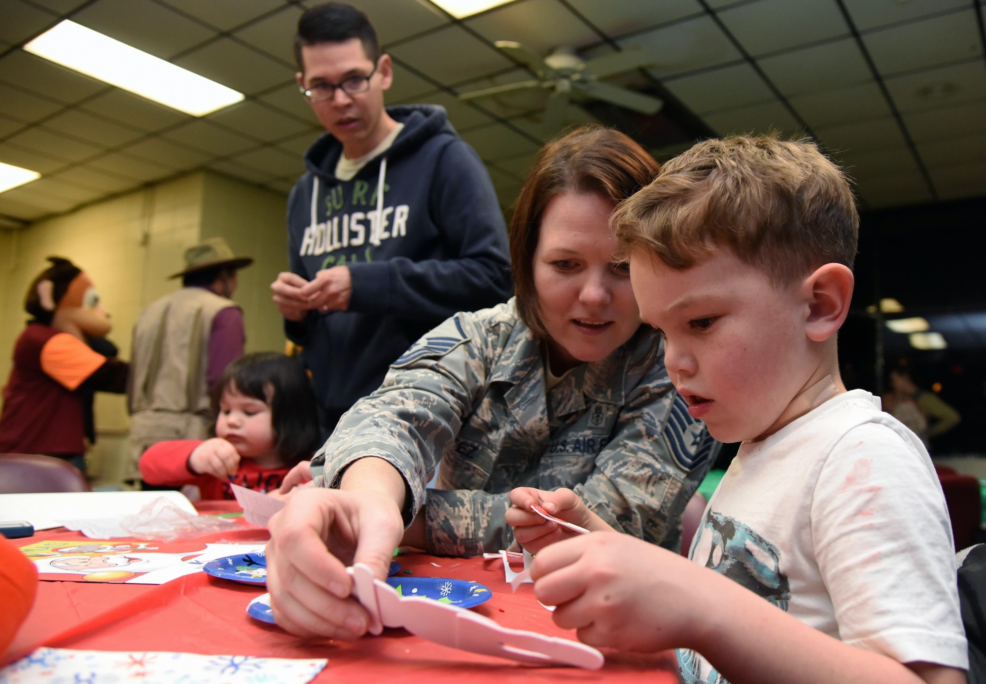 U.S. Air Force Master Sgt. Victoria Cortez, 81st Force Support Squadron Airman and Family Readiness Center NCO in charge, assists her son, Alex, with assembling an ornament during Christmas in the Park at Keesler Air Force Base, Mississippi, Dec. 6, 2018. The event hosted by Outdoor Recreation included cookie and ornament decorating, games and visits with Santa. (U.S. Air Force photo by Kemberly Groue)