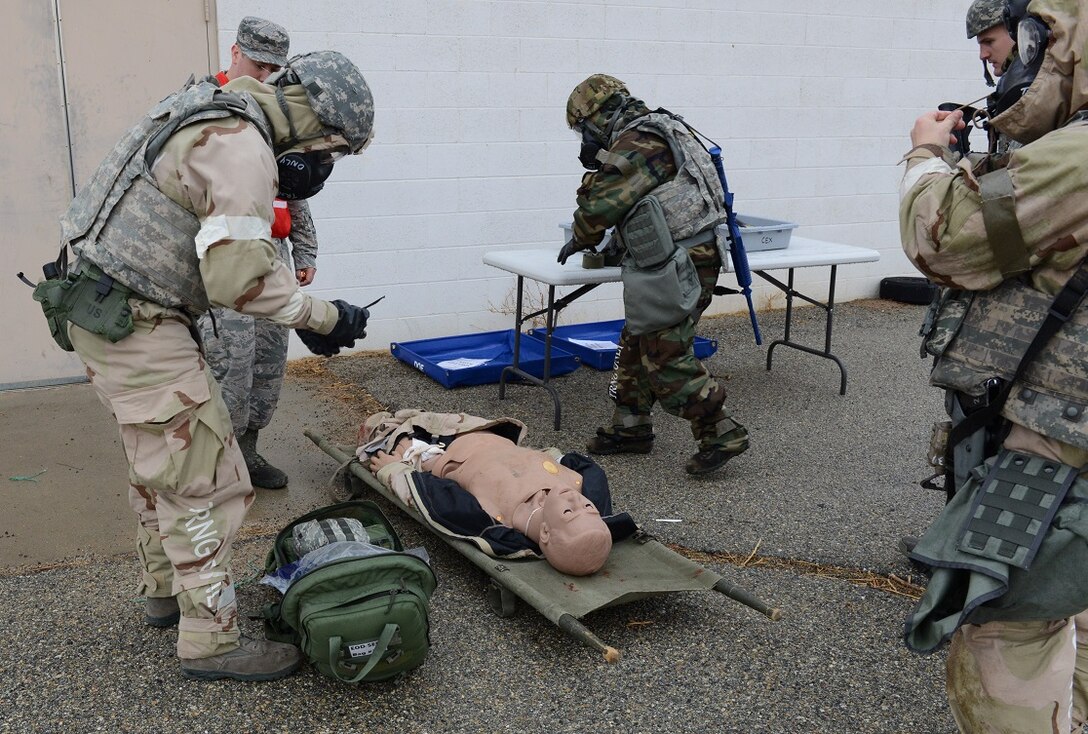 Airmen in full mission oriented protective posture gear practice first aid on a casualty dummy during the latest readiness exercise Dec. 6. (U.S. Air Force photo by Kenji Thuloweit)