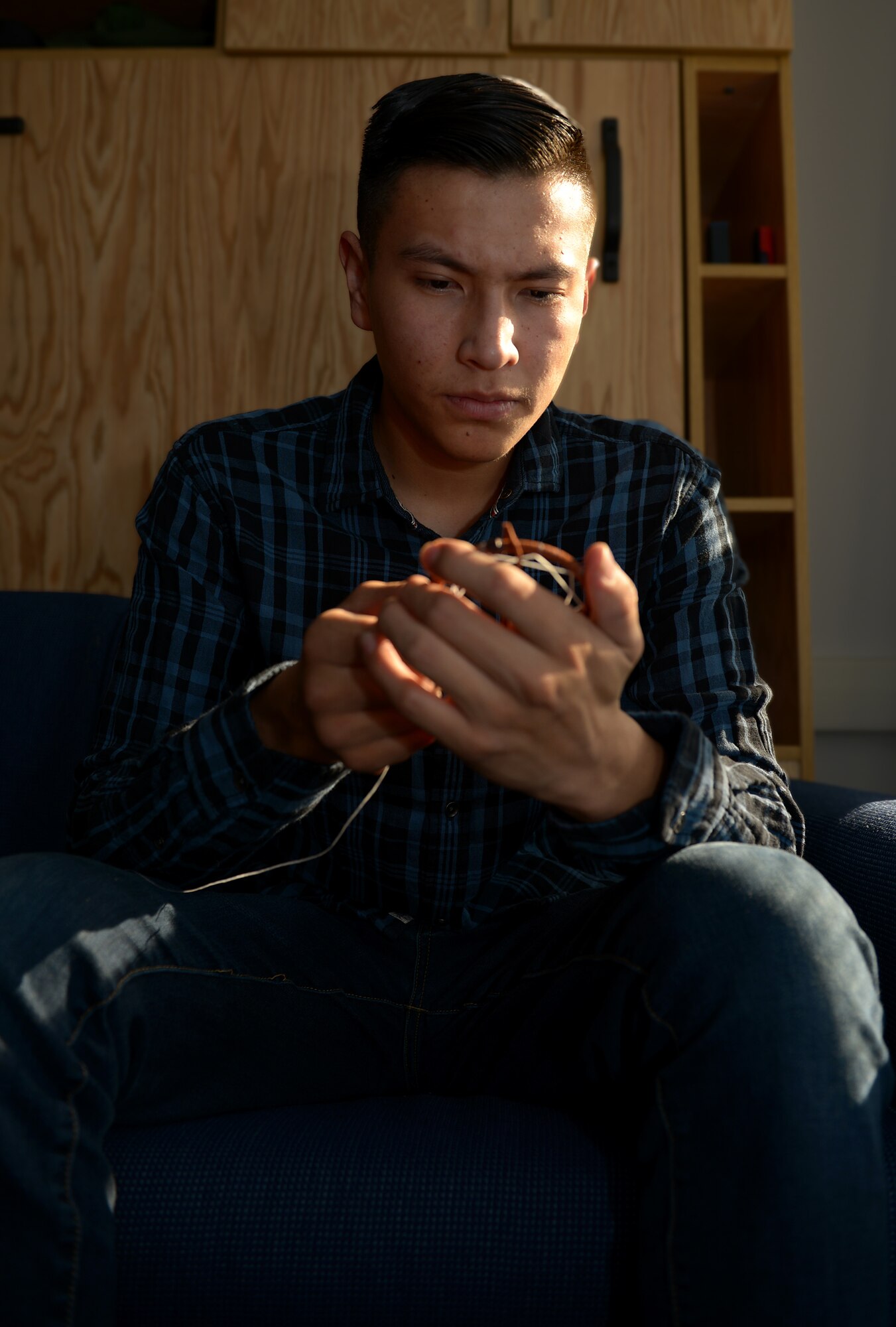 Airman 1st Class Phillip E. Rock weaves a dream catcher.