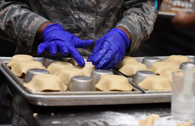 Airman 1st Class Alexis M. Taylor molds dough over a muffin pan.