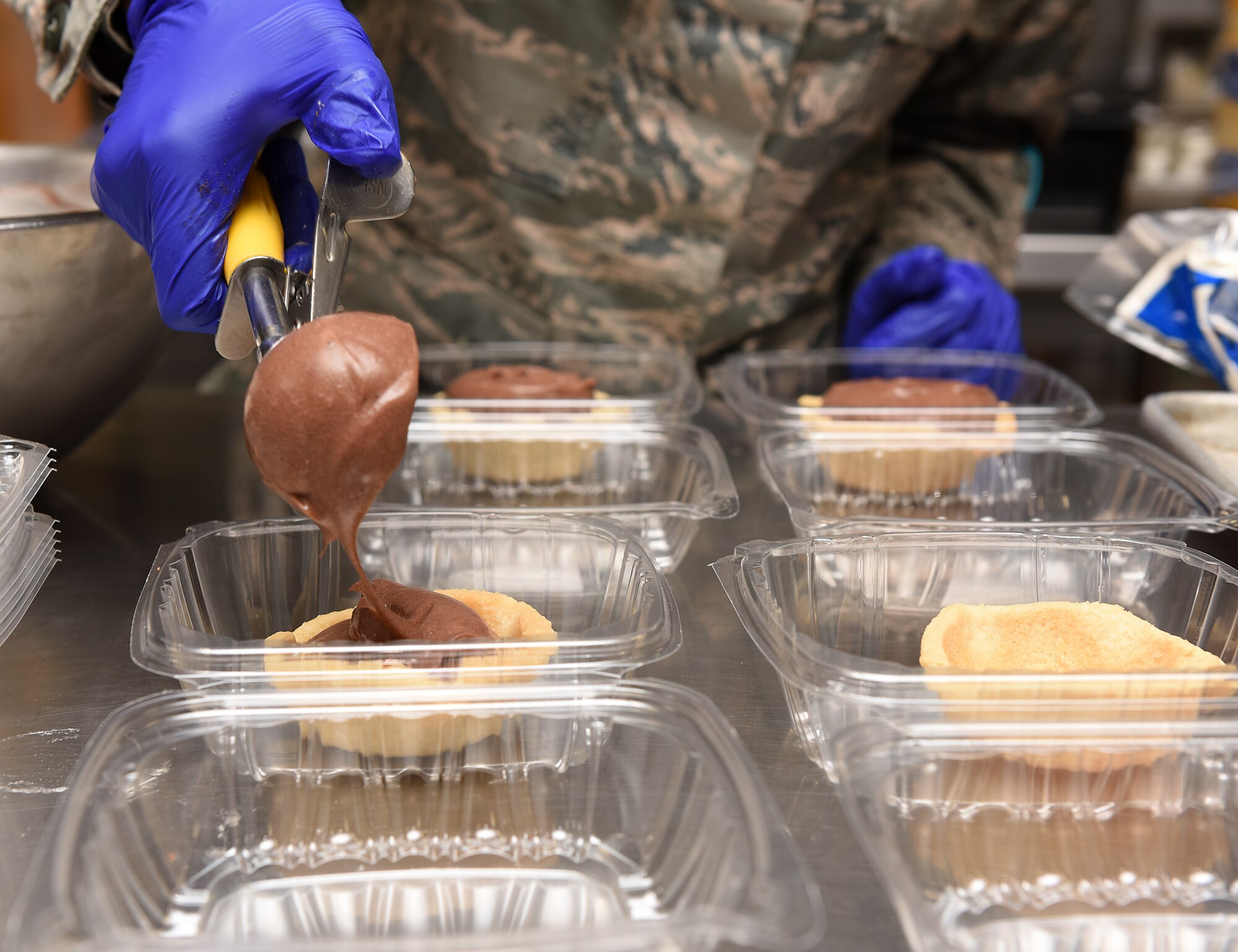 Airman 1st Class Alexis M. Taylor scoops chocolate pudding into pie crusts.