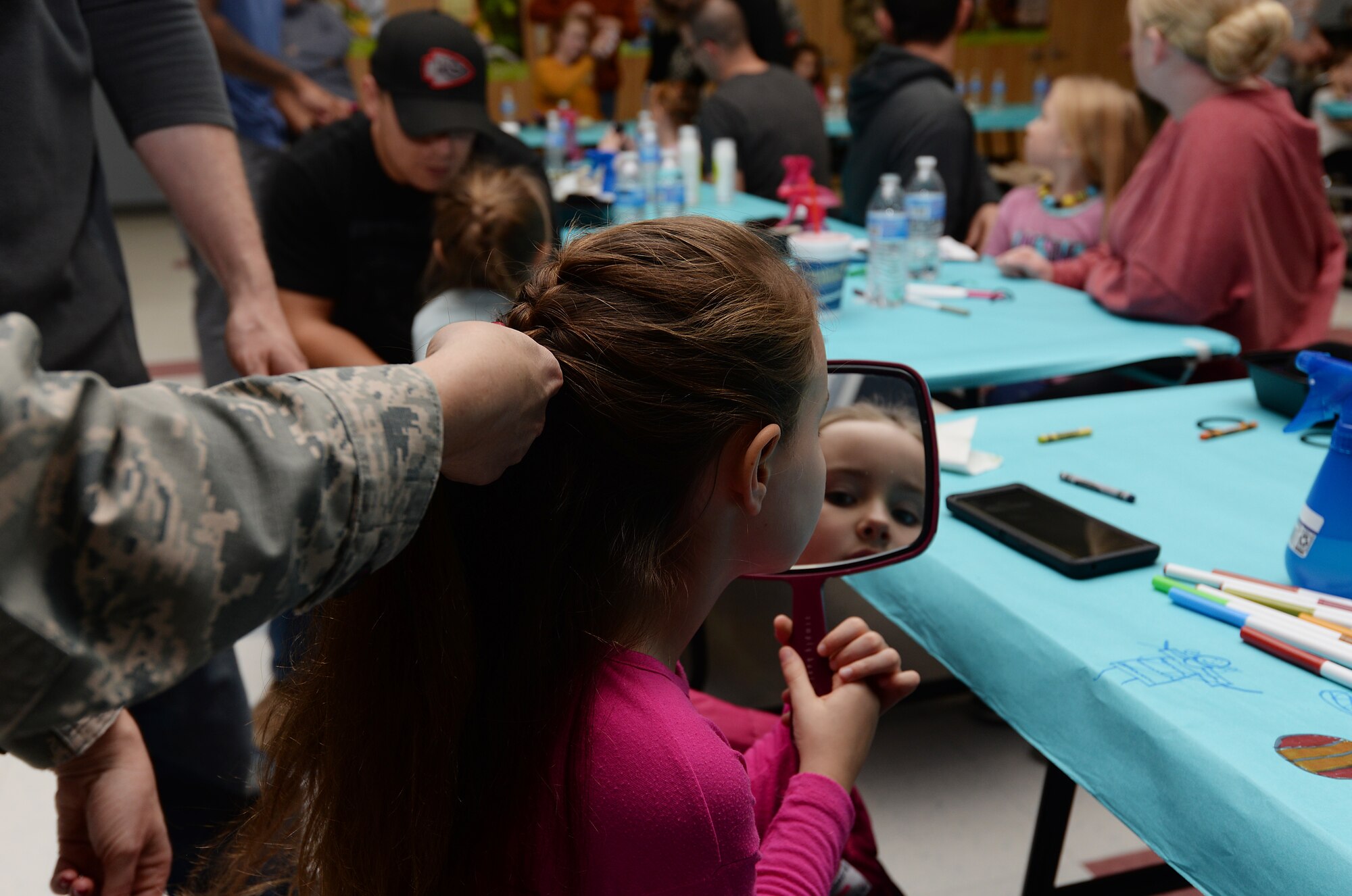 Willow Brewer looks in the mirror during the first Braids to Buns event at Whiteman Air Force Base.