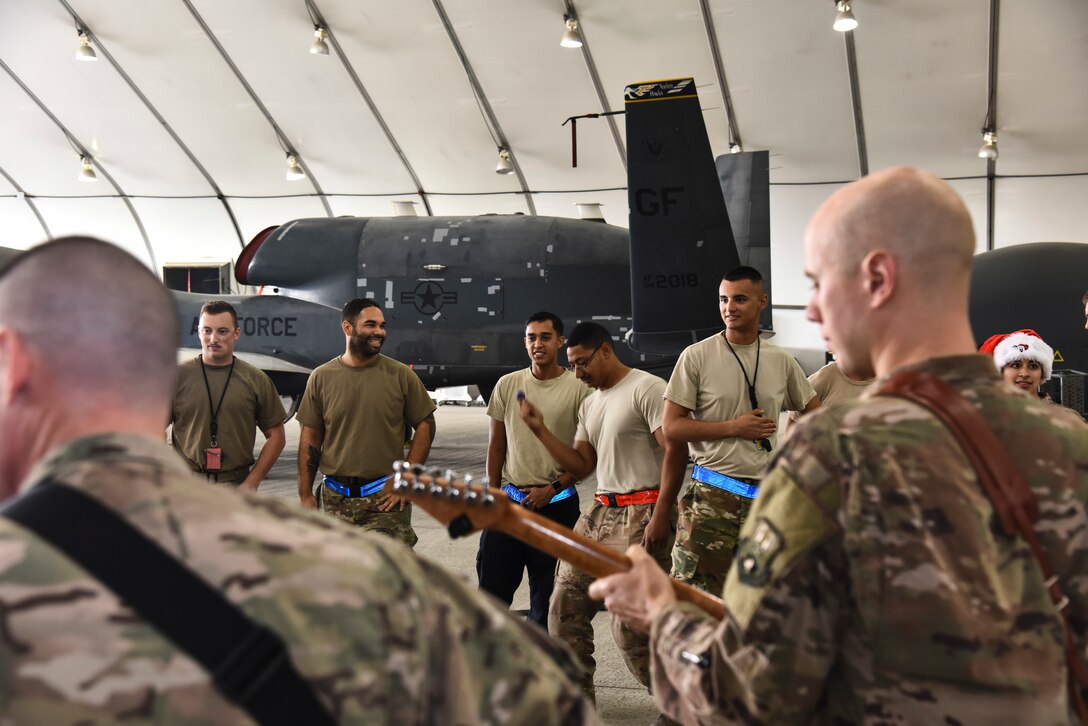 Airmen from the 380th Expeditionary Maintenance Group enjoy the U.S. Air Forces Central Command Band's performance at Al Dhafra Air Base, United Arab Emirates, Dec. 4, 2018. The AFCENT Band rotates several ensembles through the area of responsibility that perform a wide variety of musical styles to appeal to audiences of all ages and backgrounds. (U.S. Air Force photo by Senior Airman Mya M. Crosby)