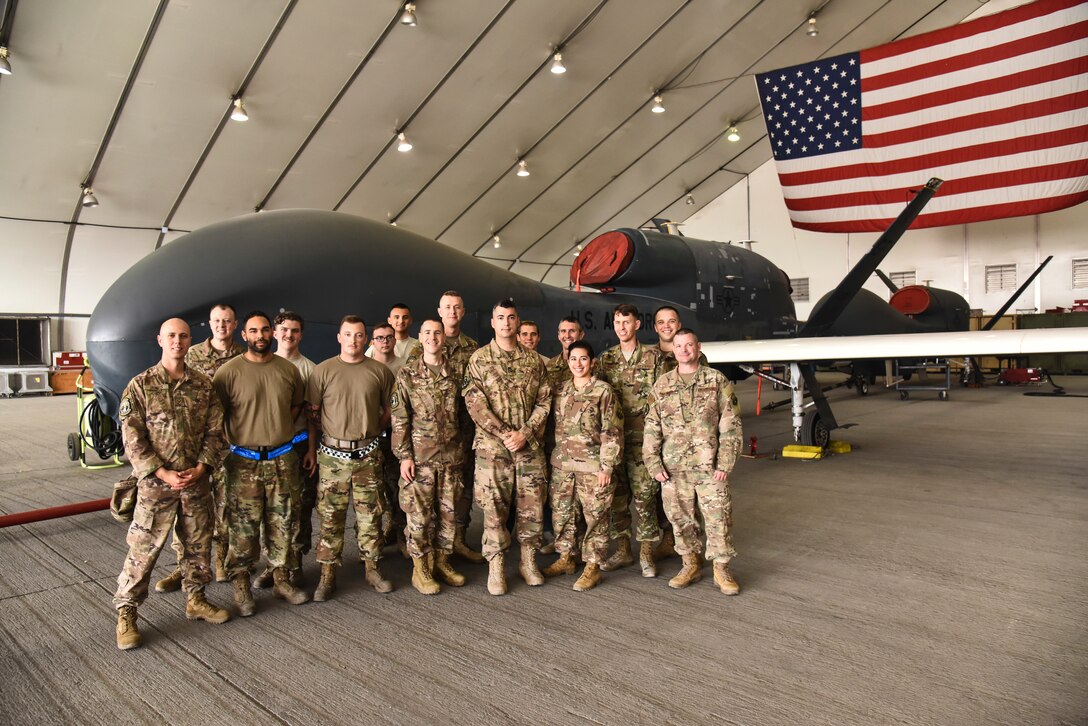 The U.S. Air Forces Central Command Band poses with 380th Expeditionary Maintenance Group Airmen at Al Dhafra Air Base, United Arab Emirates, Dec. 4, 2018. The AFCENT Band rotates several ensembles through the area of responsibility that perform a wide variety of musical styles to appeal to audiences of all ages and backgrounds. (U.S. Air Force photo by Senior Airman Mya M. Crosby)