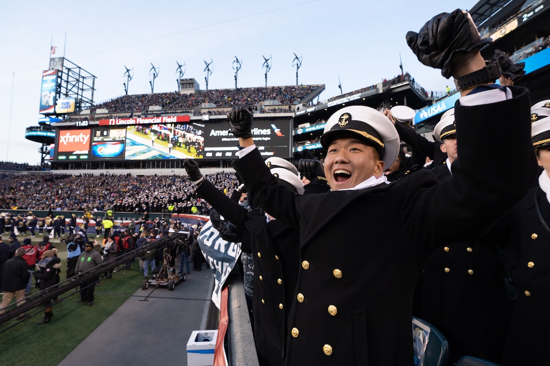 Navy Midshipmen cheer on their team during a football game.