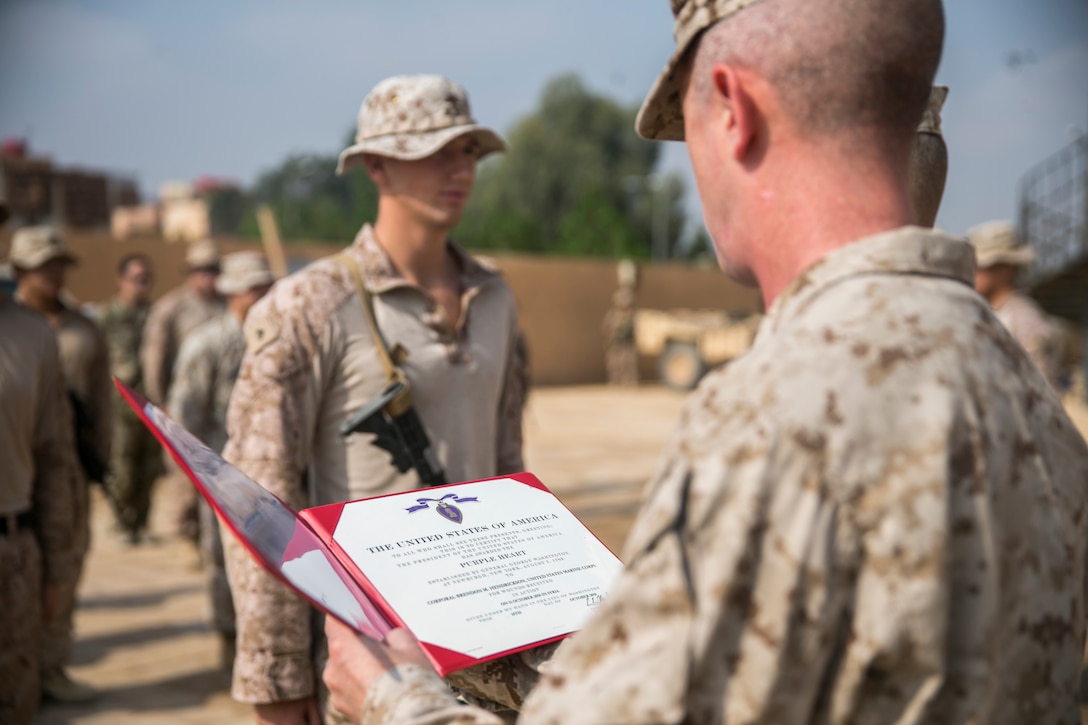 U.S. Marine Corps Sgt. Maj. William Thurber (right), the sergeant major of Marine Corps Forces Central Command, holds the Purple Heart citation for Cpl. Brendon Hendrickson (left), an anti-tank missile Marine with 3rd Battalion, 4th Marine Regiment attached to Special Purpose Marine Air-Ground Task Force, Crisis Response-Central Command, Oct. 22, 2018. Hendrickson received the Purple Heart for wounds sustained in Syria while deployed in support of operations for SPMAGTF-CR-CC.