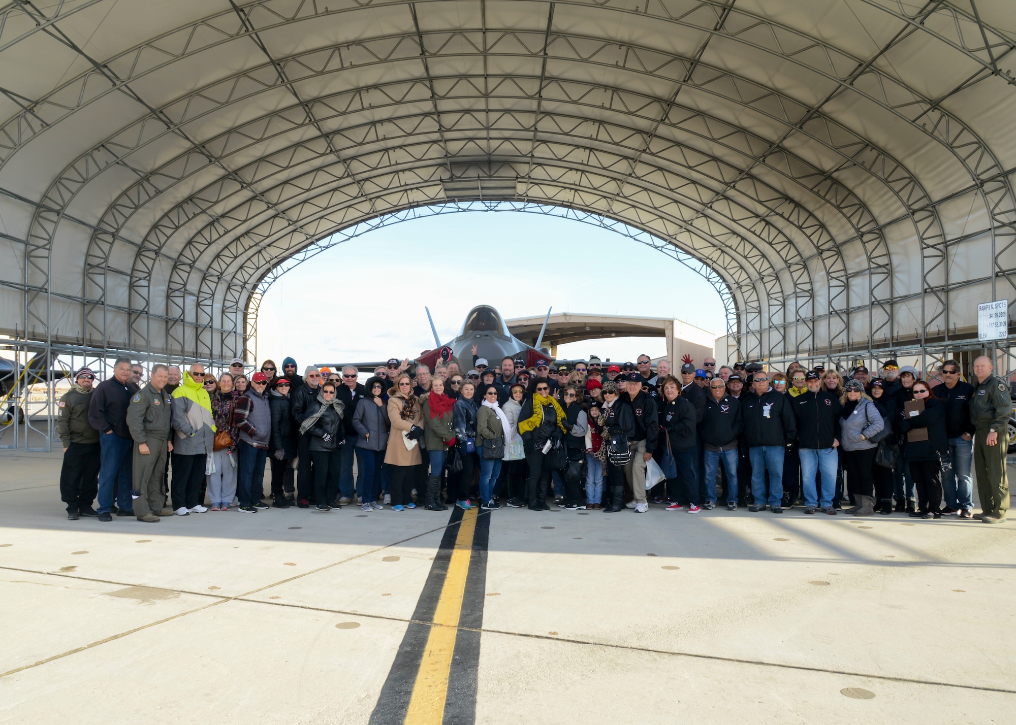 Members of local Corvette car clubs pose for a photo following a tour of an F-35 at Edwards Air Force Base, California, Nov. 30. The group provided their cars for a car show during the base's Winterfest event later that night. (U.S. Air Force photo by Giancarlo Casem)