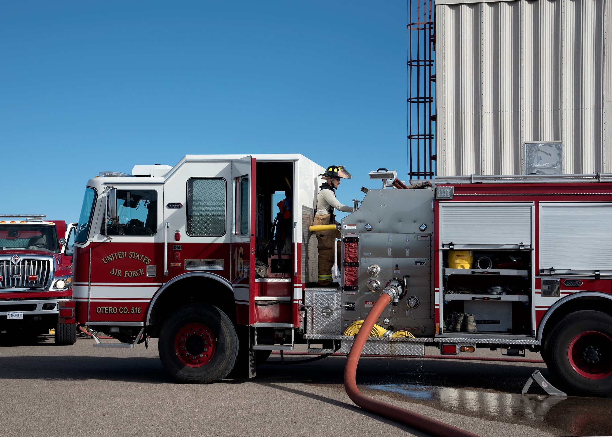 A firefighter stands on a fire truck.