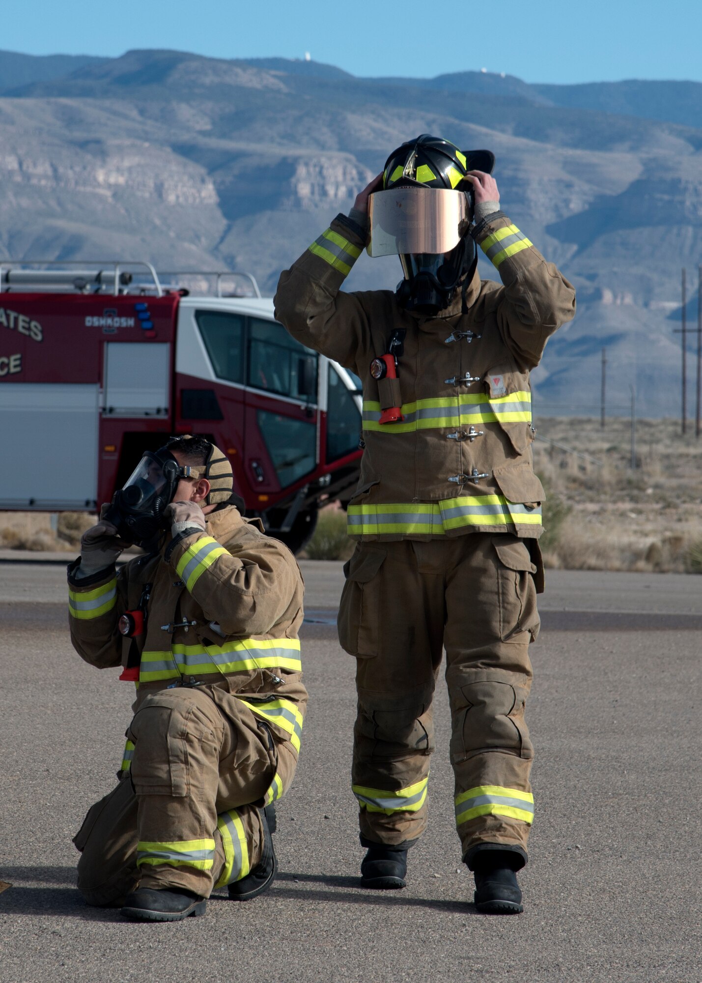 Two firefighters put on helmets.