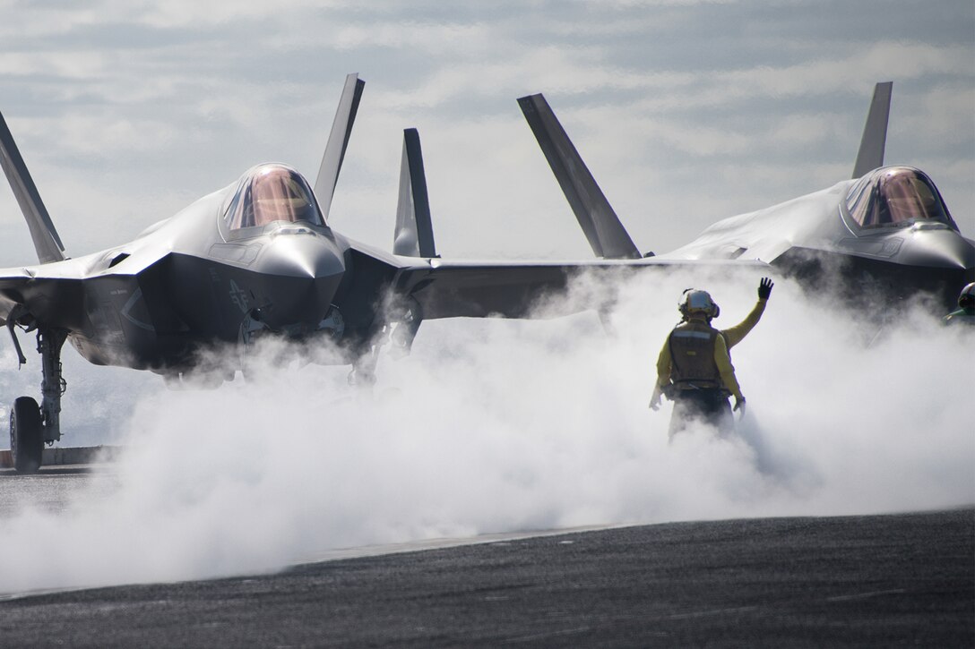 Sailors direct jets on a flight deck.