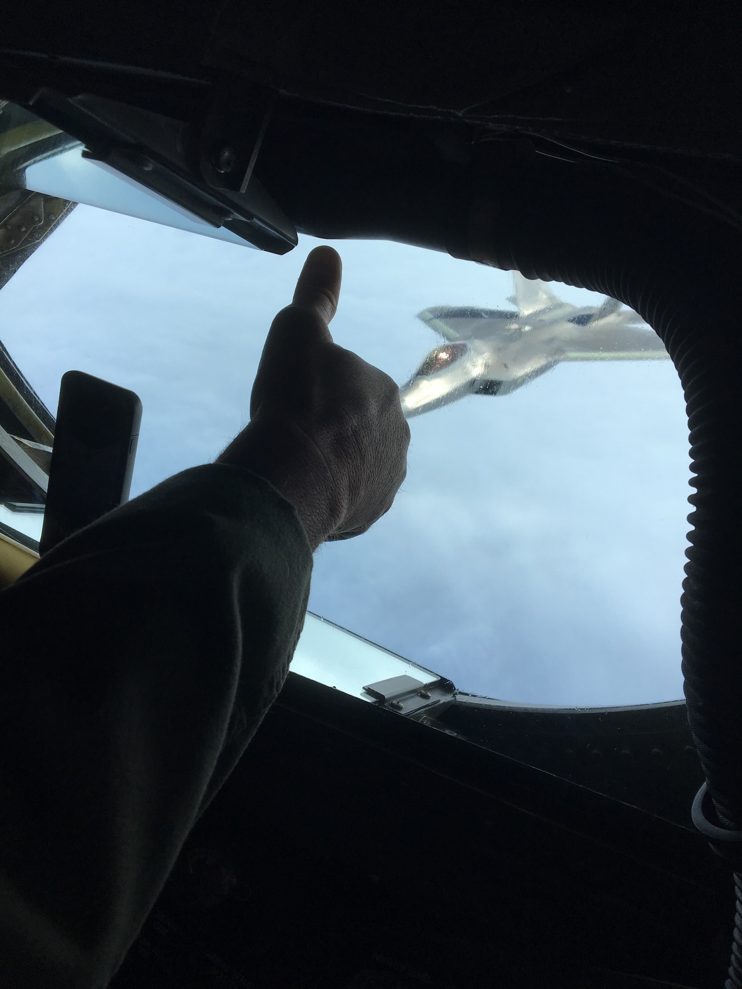 U.S. Air Force Chief Master Sgt. Steven Robinson, boom operator with the 465th Air Refueling Squadron from Tinker Air Force Base, Oklahoma, gives a thumb up to the pilot of an F-22 Raptor Nov. 5, 2018, flying from Tyndall Air Force Base, Florida to Hill Air Force Base, Utah, for depot maintenance.