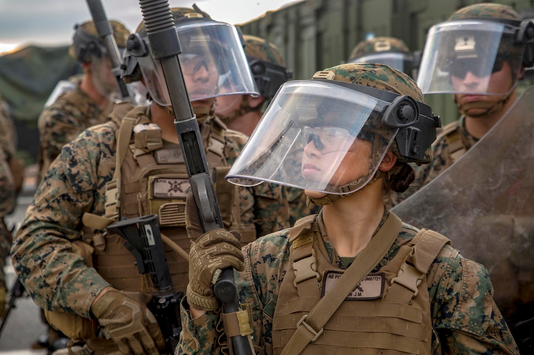 Marines patrol an area with police gear on.