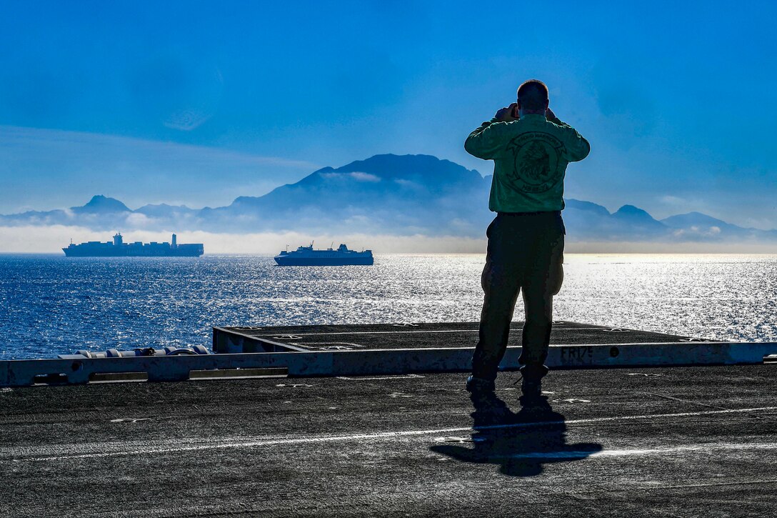 A sailor uses binoculars to look at the African side of the Straight of Gibraltar.