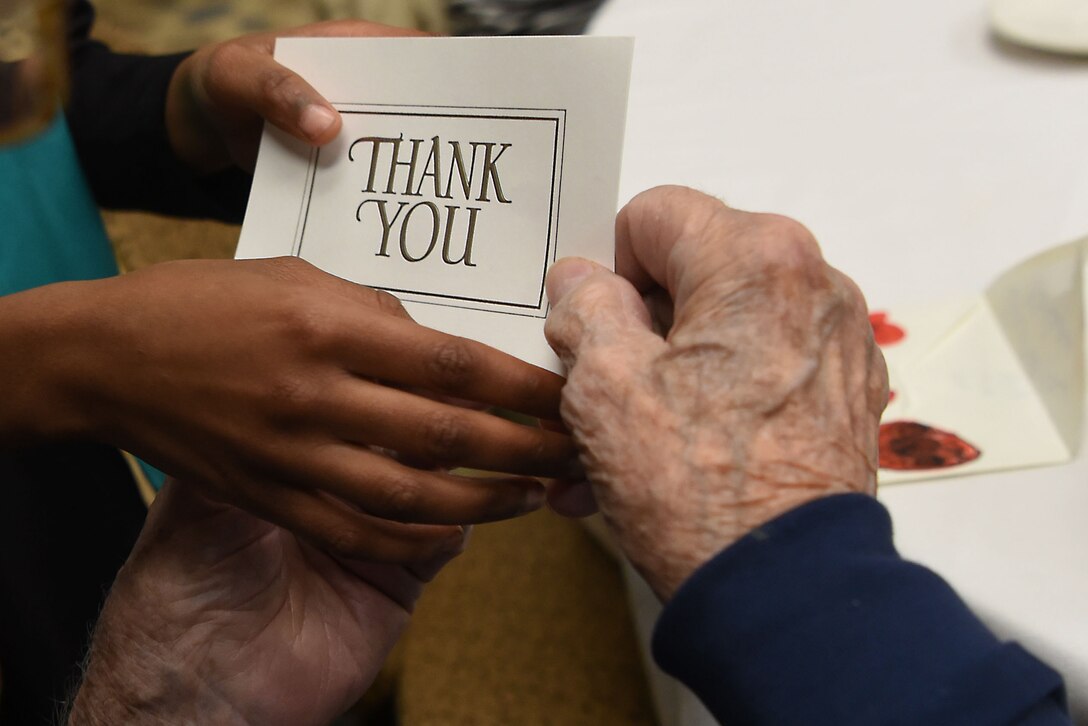 The hands of a child and an old man hold a thank you card.