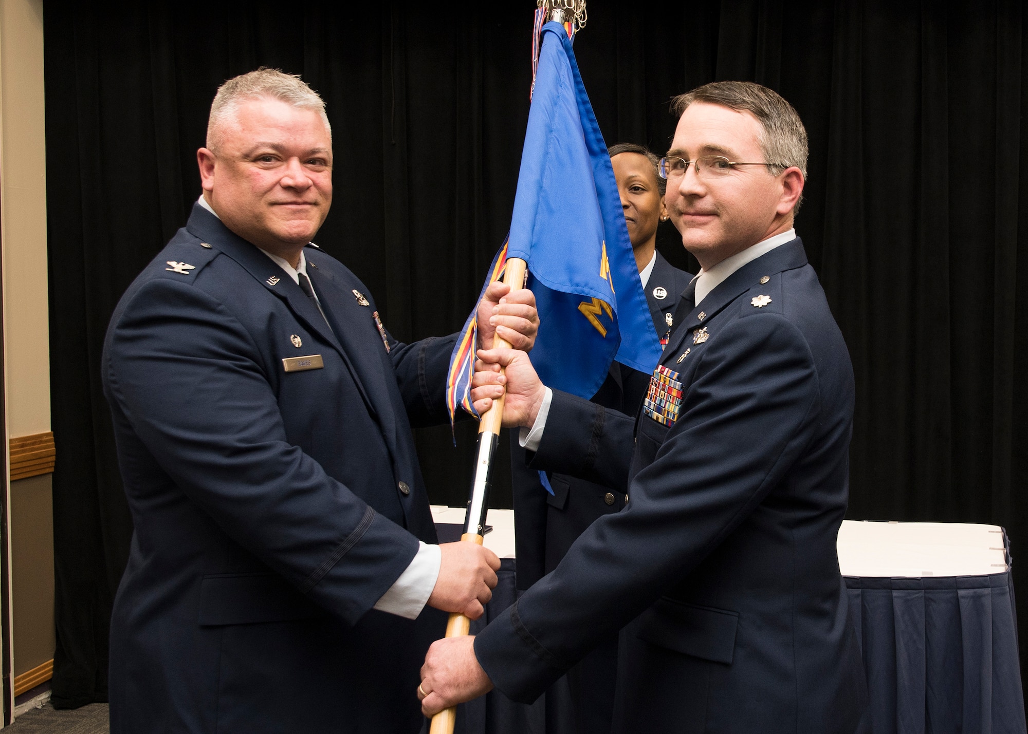 Lt. Col Russell Kohl receives the Medical Group guidon from Col Ken Eaves, 131st Bomb Wing Commander, during the change of command ceremony at Whiteman Air Force Base, Dec. 2. Kohl assumes command from Col. Patti Fries, who continues her military service as the commander of the Nebraska Air National Guard’s 155th Medical Group, a subordinate unit of the 155th Air Refueling Wing, at Lincoln Air National Guard Base.  (U.S. Air National Guard photo by Airman 1st Class Joseph Geldermann)