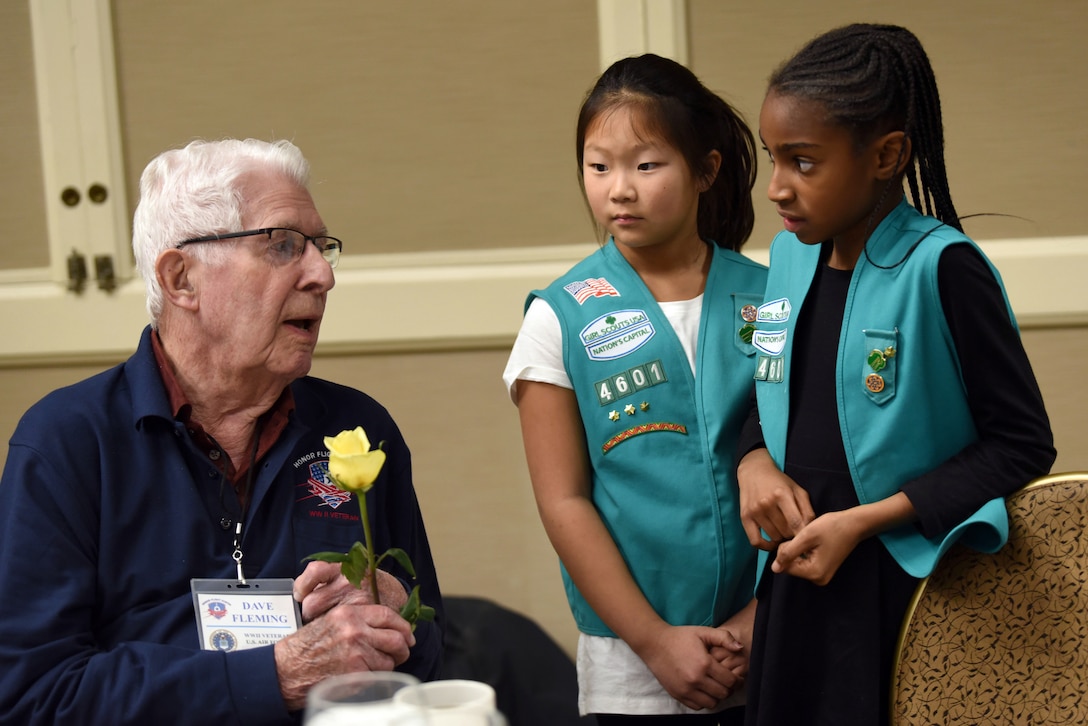 A veteran talks to two Girl Scouts.