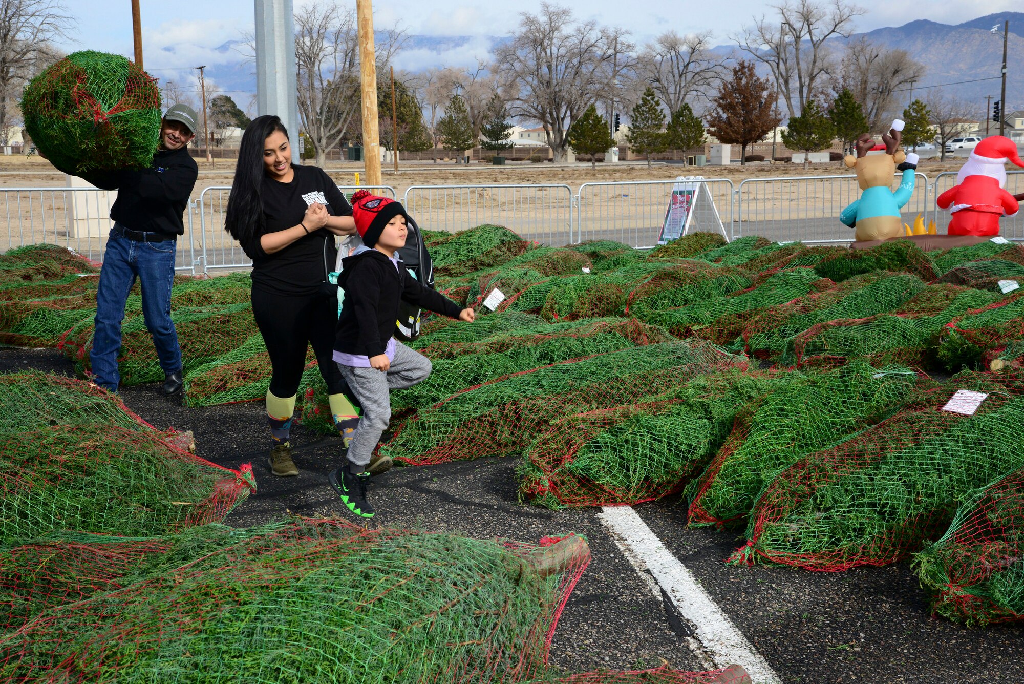 Matt Montano, Kirtland Force Support Squadron director carries a tree for Angelica Romero, and her children, Konnor and Brantley Romero. Romero picked out her tree during the Trees for Troops event Dec. 7 at the Chapel here. The two-day event provided free trees for members of Team Kirtland. Last year the program delivered 17,400 Christmas trees to 70 U.S. military bases; 250 trees delivered to four international bases; and is in its 14th year. (U.S. Air Force photo by Jessie Perkins)