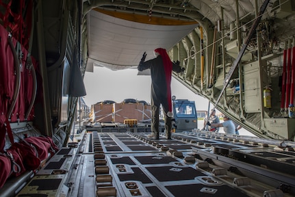 Senior Airman Walter Frank, 36th Airlift Squadron loadmaster, directs an equipment operator from the 374th Logistics Readiness Squadron into position during Operation Christmas Drop 2018 at Andersen Air Force Base, Guam, Dec. 9, 2018. Prior to being loaded onto the planes, the 374th LRS Combat Mobility Flight packs the parachutes and builds the Coastal Humanitarian Air Drop bundles that will be used throughout OCD.