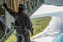 Senior Airman Kylie Hanni, 36th Airlift Squadron loadmaster out of Yokota Air Base, Japan, confirms the airdrop made hit its mark while flying over the island of Nama, Federated States of Micronesia during Operation Christmas Drop 2018, Dec. 10, 2018. In its 67th year, OCD is the world’s longest running airdrop training mission providing critical supplies to 56 Micronesian islands impacting approximately 20,000 people across 1.8 million square nautical miles of operating area.