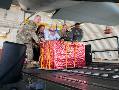 From left, Maj. Gen. John Gordy, commander, U.S. Air Force Expeditionary Center; Heather Coble, deputy chief of mission, Kolonia, Pohnpei and Federated States of Micronesia; Bruce Best, researcher, University of Guam; Brig. Gen. Gentry Boswell, commander, 36th Wing; and Col. Otis Jones, commander, 374th Airlift Wing push a box of humanitarian goods into a C-130 during the Operation Christmas Drop Push Ceremony at Andersen Air Force Base Dec. 10.  During the ceremony, the first of nearly 100 boxes of humanitarian goods was pushed into the C-130 before being delivered to 56 islands across the Commonwealth of the Northern Mariana Islands, the FSM and the Republic of Palau.