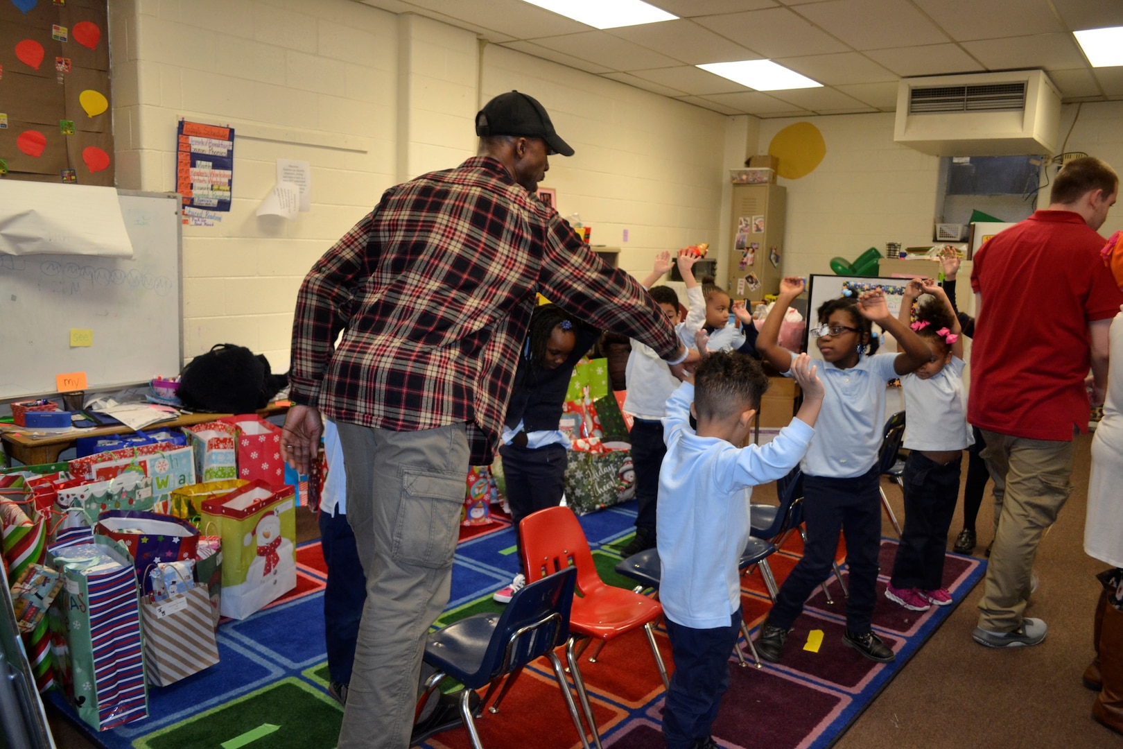 Shahid Wilds, a Medical supply chain employee, left middle, plays with students during the annual Children’s Holiday Party at Benjamin Franklin Elementary School Dec. 6, 2018 in Philadelphia.
