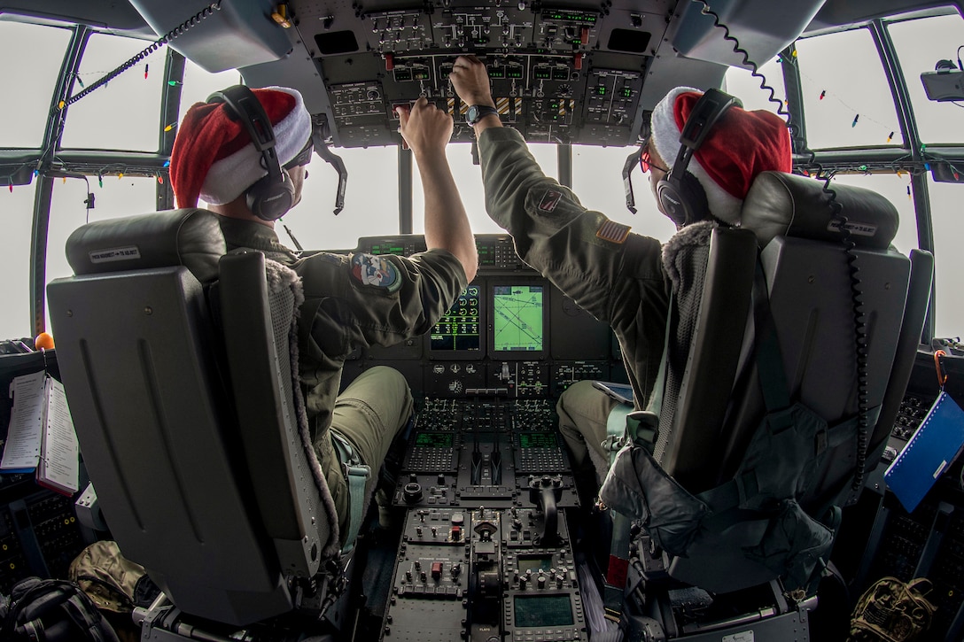 Two pilots adjust controls in a cockpit.