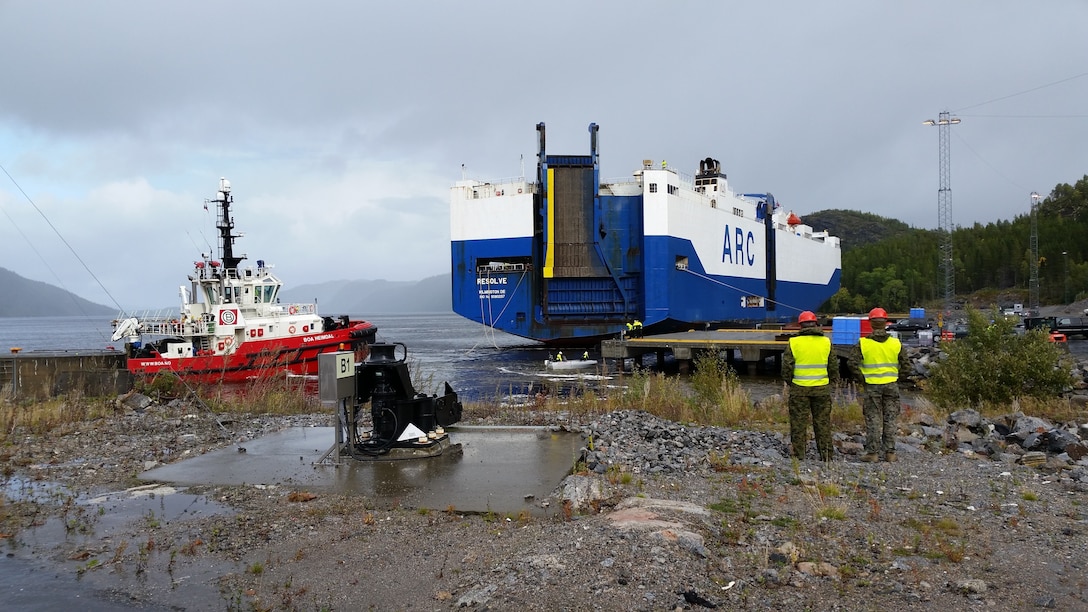 U.S. Marines with II Marine Expeditionary Force, standby to off-load equipment for NATO exercise Trident Juncture from the American Roll-on Roll-off Carrier Resolve in Hammernesodden, Norway, Sept. 23, 2018. Marines and service members from the Norwegian Armed Services unloaded nearly 200 military vehicles and more than 70 containers with military equipment in two days despite cold weather with periods of rain and sleet. (Photo by Kyle Soards)