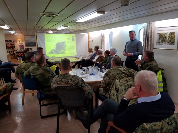 U.S. Marines assigned to II Marine Expeditionary Force, Norwegian service members and federal employees of Norway attend a brief regarding the off-loading of military vehicles and equipment in preparation for NATO exercise Trident Juncture 18 from American Roll-on Roll-off Carrier Resolve in Hammernesodden, Norway, Sept. 24, 2018. Marines and service members from the Norwegian Armed Services unloaded nearly 200 military vehicles and more than 70 containers with military equipment in two days despite cold weather with periods of rain and sleet. (U.S. Marine Corps photo by Kyle Soard)