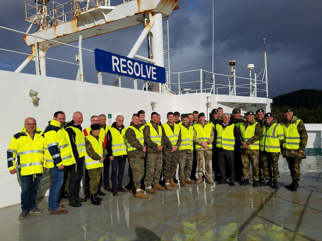 U.S. Marines with II Marine Expeditionary Force, Norwegian service members and federal employees of Norway pose after off-loading military vehicles and equipment in preparation for NATO exercise Trident Juncture from American Roll-on Roll-off Carrier Resolve in Hammernesodden, Norway, Sept. 24, 2018. Marines and service members from the Norwegian Armed Services unloaded nearly 200 military vehicles and more than 70 containers with military equipment as planned in two days despite cold weather with periods of rain and sleet. (photo by Kyle Soard)