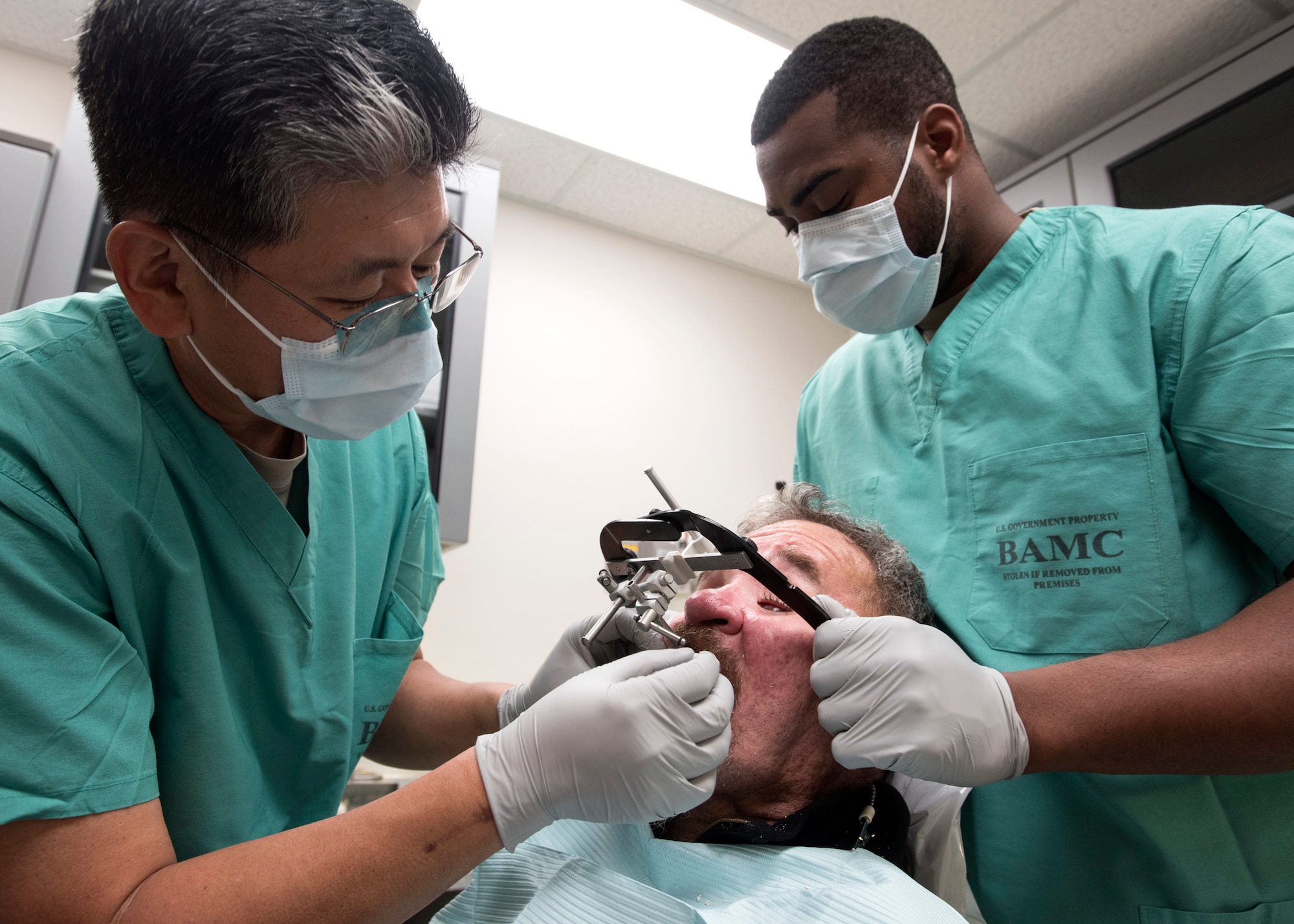 Lt. Col. (Dr.) Young J. Honnlee (left), 59th Medical Wing maxillofacial prosthodontics fellow, and Senior Airman Christopher Walker, 59th Dental Training Squadron dental assistant, places a facebow on a patient at San Antonio Military Medical Center, Joint Base San Antonio-Fort Sam Houston, Texas. The facebow records the relationship of the jaws to the temporomandibular joints; the record may then be used to orient a cast or model of the maxilla to the articulator. (U.S. Air Force photo by Staff Sgt. Kevin Iinuma)