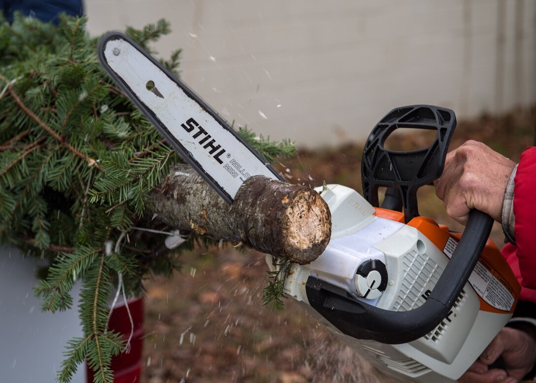 A volunteer cuts the bottom of a Christmas tree during the Christmas SPIRIT Foundation’s Trees for Troops program at Bethel Park, Hampton, Virginia, Dec. 7, 2018.