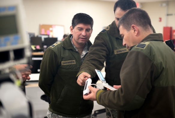 Medical health officers from the Chilean Air Force look at a hand-held ultrasound unit on Dec. 7, at Camp Bramble on Joint Base San Antonio-Lackland, Texas. The Chileans visited the 59th Medical Wing to gain a better understanding of Critical Care Air Transportation Teams and the advanced equipment available during each mission. (U.S. Air Force photo by Kiley Dougherty)