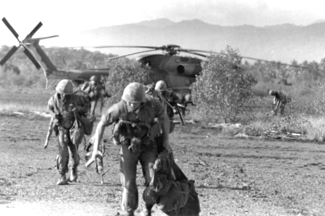 Marines run from helicopter.