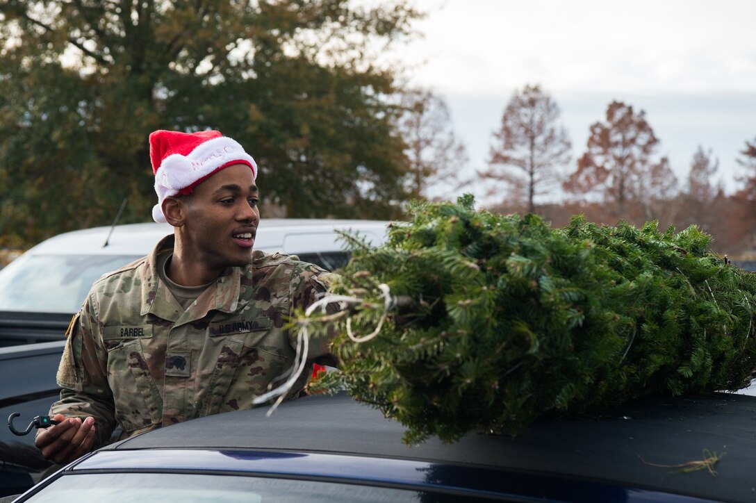 U.S. Army Spc. Sergio Barbel, 331st Transportation Company, 11th Trans. Battalion, 7th Trans. Brigade (Expeditionary) watercraft engineer, ties a tree to the top of a car during the Christmas SPIRIT Foundation’s Trees for Troops program at Joint Base Langley-Eustis, Virginia, Dec. 7, 2018.