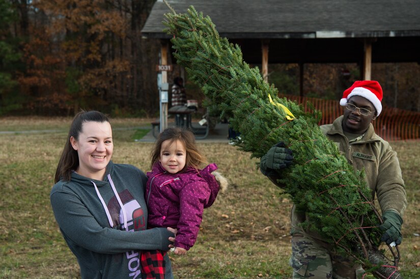 (Right) U.S. Army Spc. Olander Albright, 612th Movement Control Team, 53rd Transportation Battalion, 7th Trans. Brigade (Expeditionary) movement specialist, assists Stephanie Fraley, spouse of Staff Sgt. Brian Fraley, 128th Aviation Brigade instructor, during the Christmas SPIRIT Foundation’s Trees for Troops program at Joint Base Langley-Eustis, Virginia, Dec. 7, 2018.